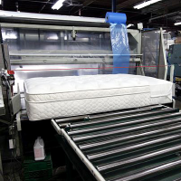 A finished mattress enters the high speed bagging machine.